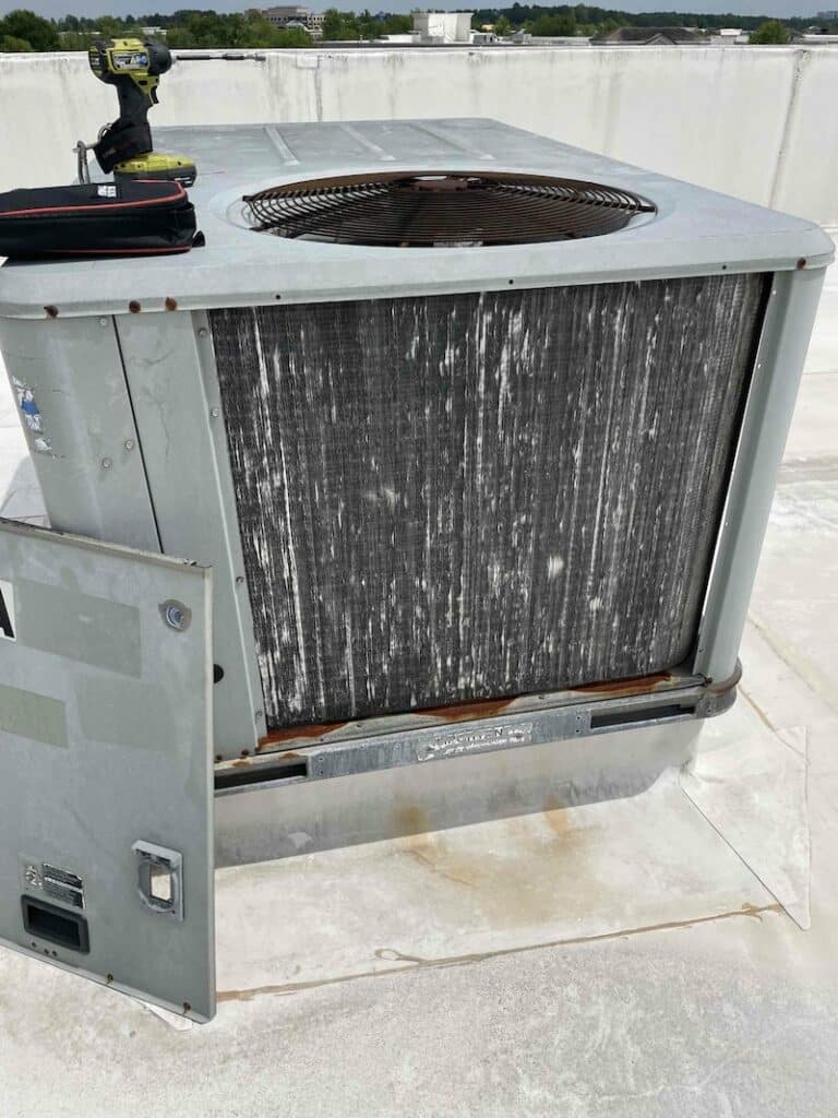 This air conditioning unit is in need of repair on top of a commercial building